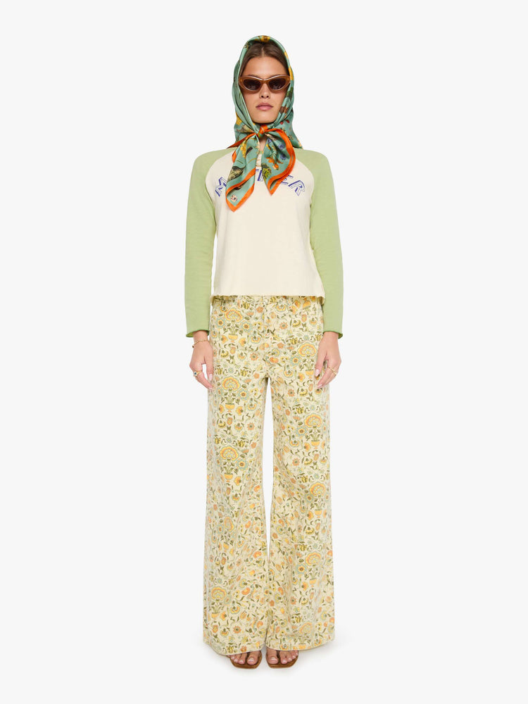 On model wearing view of a teal-green scarf with oversized printed flowers, gems, and creatures throughout.