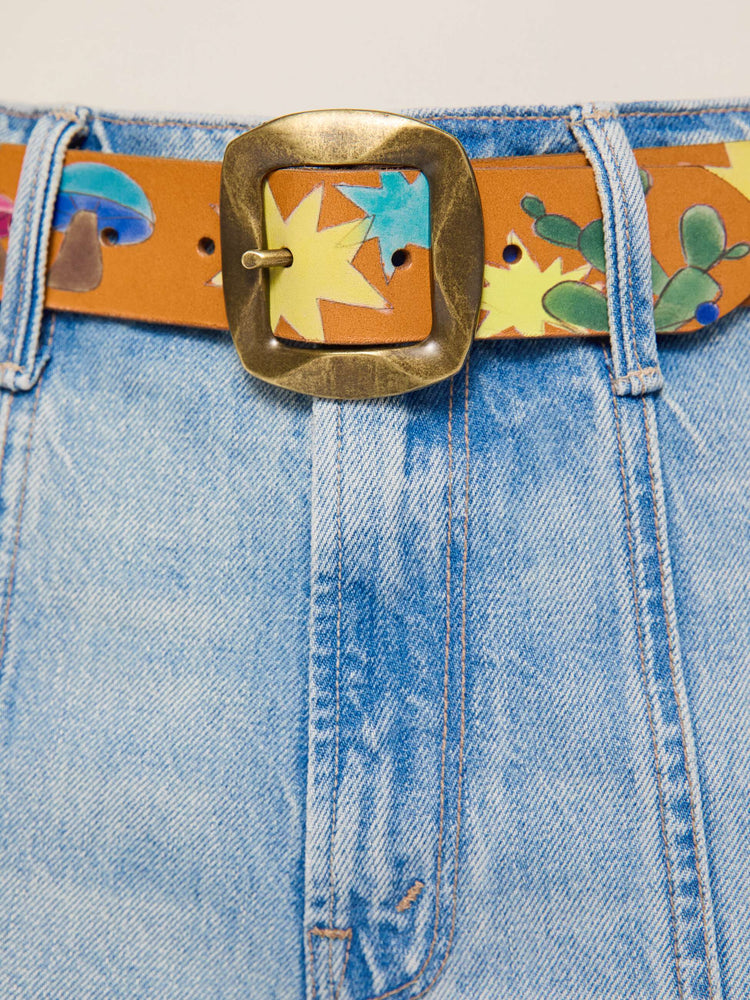 on model view of a belt made from 100% leather in tan with hand-painted stars, mushrooms and rainbow stripes, and an oversized brass buckle.