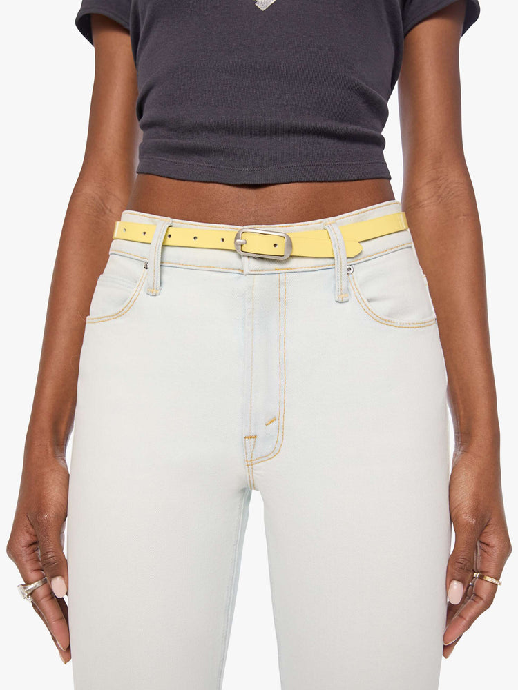 On model view of a narrow belt is made from 100% leather with a pastel yellow coating and silver hardware.