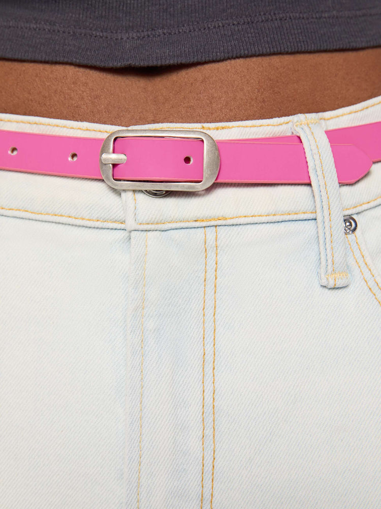 Close up on model view of a narrow belt is made from 100% leather with a pastel pink coating and silver hardware.