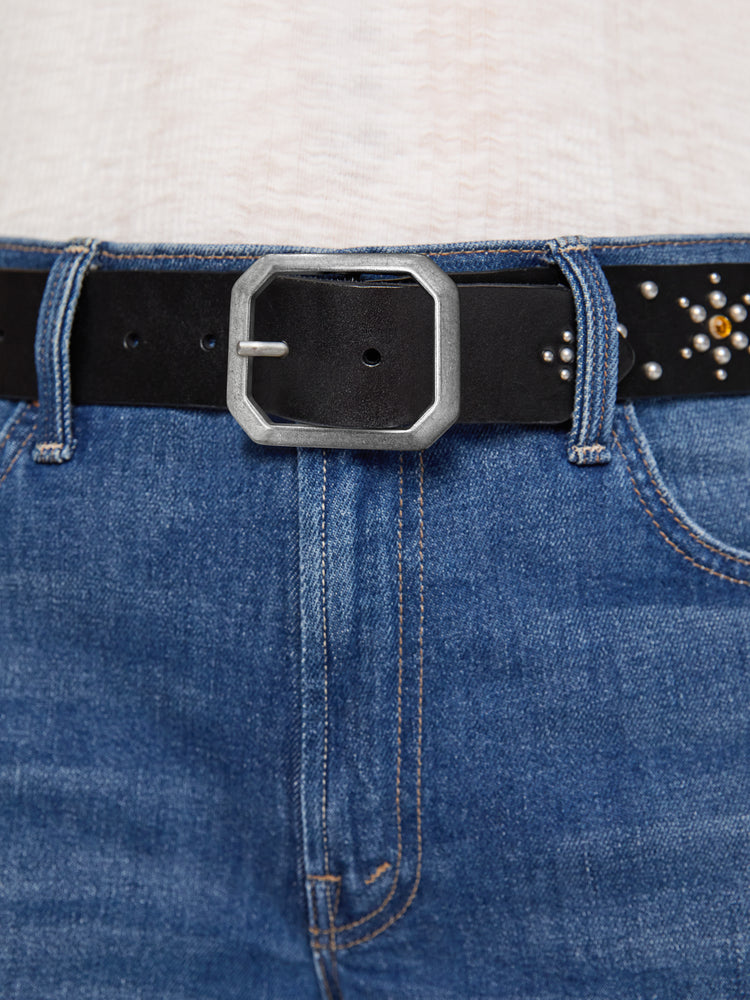 On model view of a wide belt made from 100% leather in black with an oversized metal buckle, studded stars, rhinestone details and an explicit message across the back.