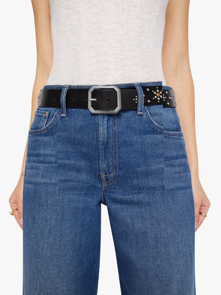On model view of a wide belt made from 100% leather in black with an oversized metal buckle, studded stars, rhinestone details and an explicit message across the back.