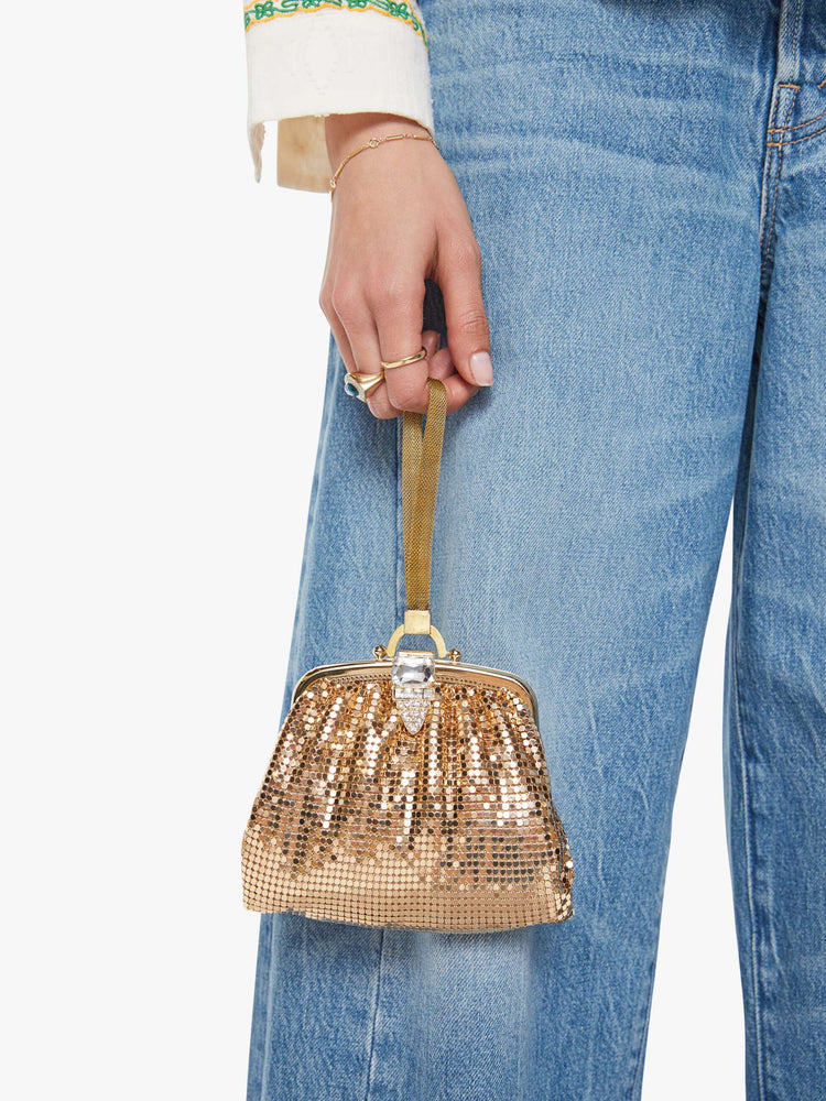 On model view of a  vintage-inspired wristlet with a clasp closure and short strap.