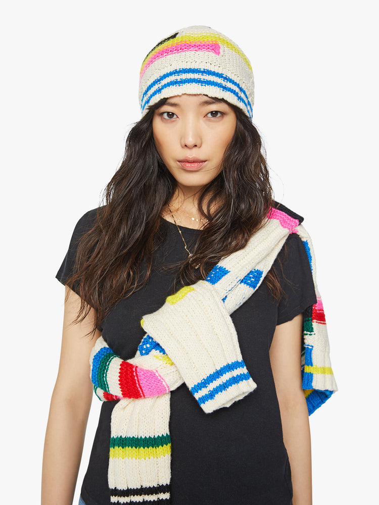 Front view a knit beanie with a ribbed hem and a snug fit in an off-white with colorful stripes, checks and cable knits details.