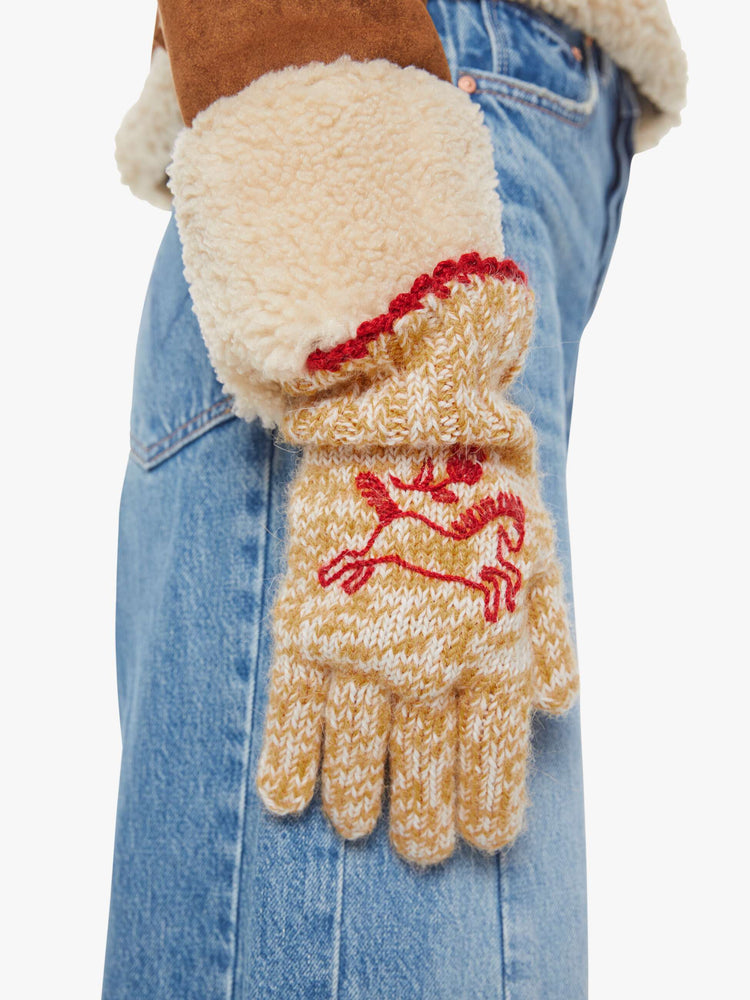 On model view of a woman in marled golden-yellow and white with red embroidered horses and trim gloves.
