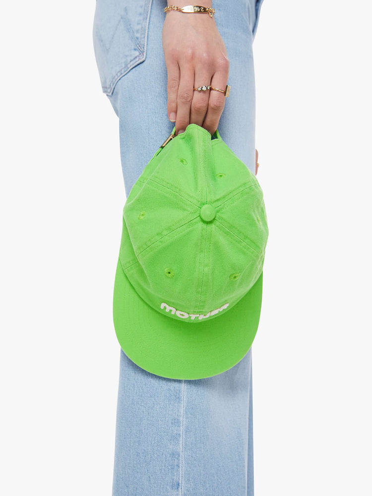 On hand view with a dad hat designed in lime green.