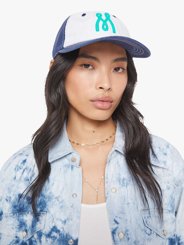 Front view of a woman dad hat designed in white and navy 100% cotton with white stitching and an M embroidered in teal on the front.