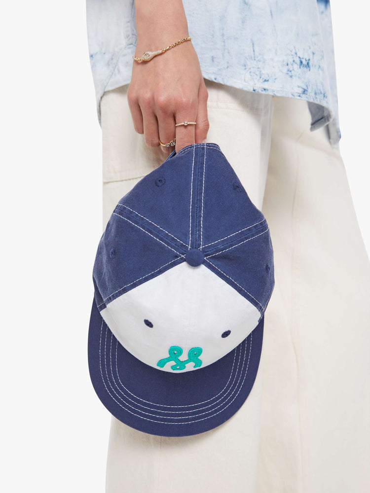 Model view of a woman dad hat designed in white and navy 100% cotton with white stitching and an M embroidered in teal on the front.
