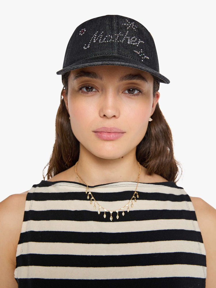 Front view of a woman in a dad hat designed in a faded black 100% cotton denim with MOTHER's name in rhinestones on the front.