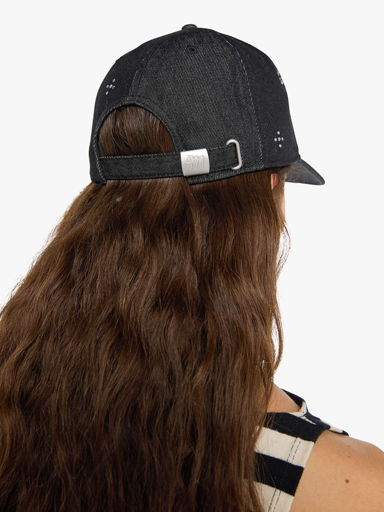 Back view of a woman in a dad hat designed in a faded black 100% cotton denim with MOTHER's name in rhinestones on the front.