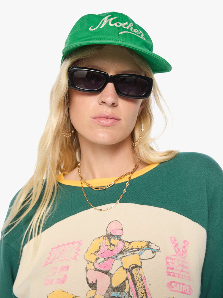 Front view of a woman in a dad hat designed in green 100% cotton with MOTHER's name embroidered in cream text on the front.