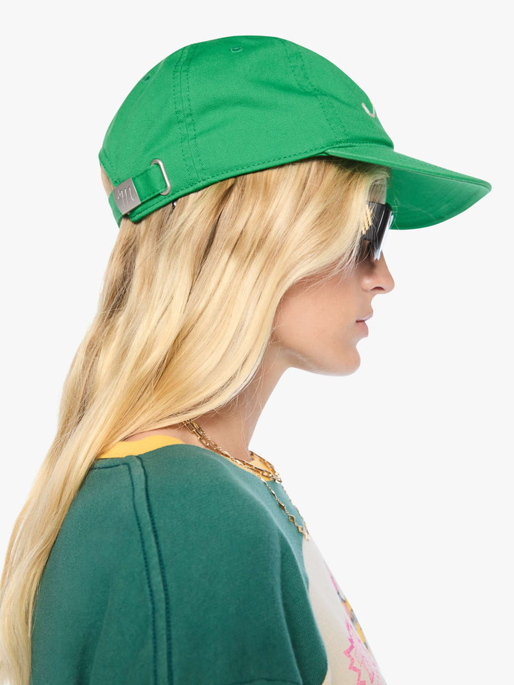 On model view of a woman in a dad hat designed in green 100% cotton with MOTHER's name embroidered in cream text on the front.