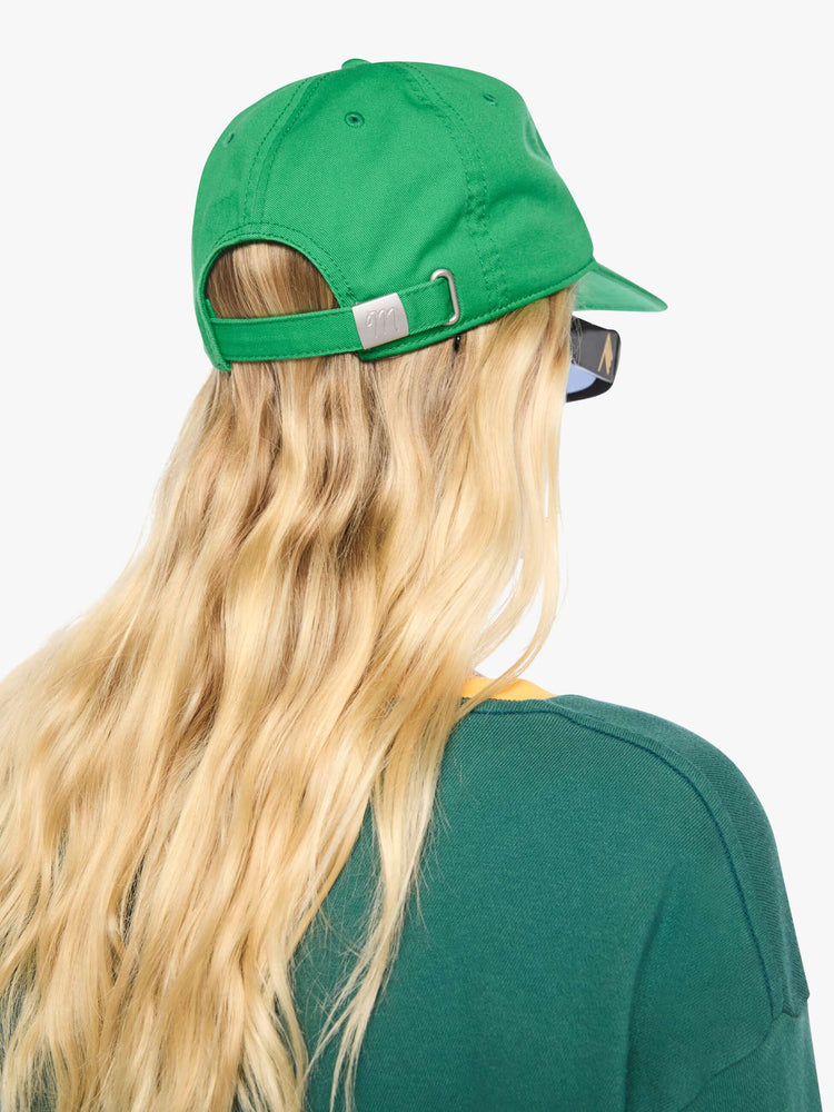 On model back view of a woman in a dad hat designed in green 100% cotton with MOTHER's name embroidered in cream text on the front.