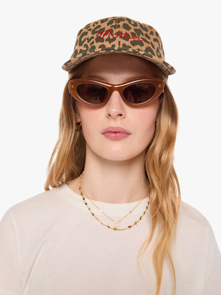 Front view of a woman in a dad hat designed in leopard print with MOTHER's name embroidered in red cursive on the front.