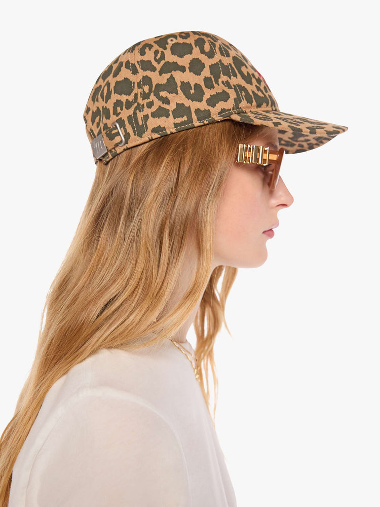 Side view of a woman in a view of a woman in a dad hat designed in leopard print with MOTHER's name embroidered in red cursive on the front.