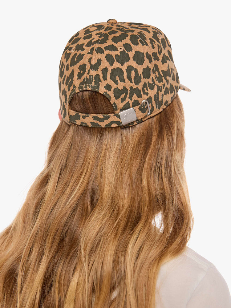 Back view of a woman in a dad hat designed in leopard print with MOTHER's name embroidered in red cursive on the front.