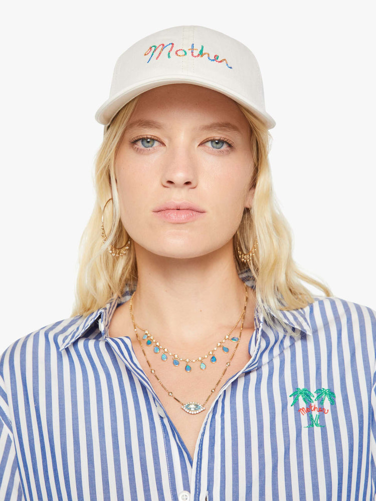 Front view of a woman in a dad hat designed in white 100% cotton with MOTHER's name embroidered in rainbow text on the front.