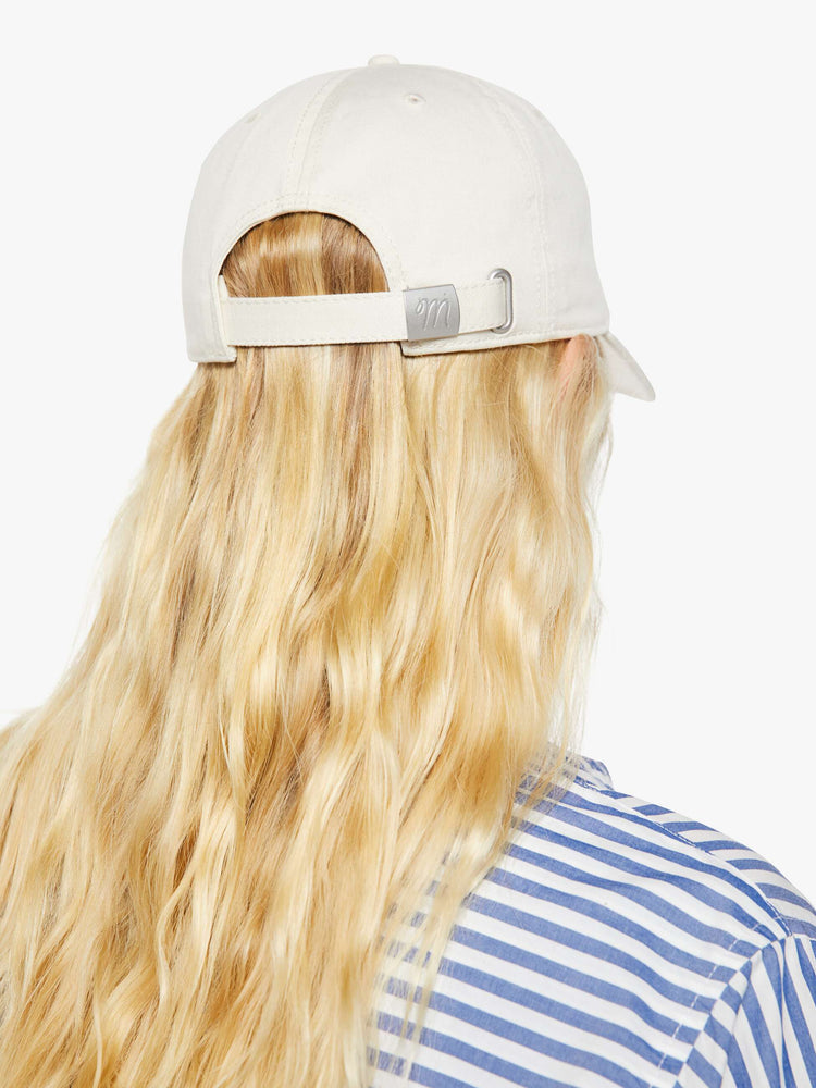 Back view of a woman in a dad hat designed in white 100% cotton with MOTHER's name embroidered in rainbow text on the front.