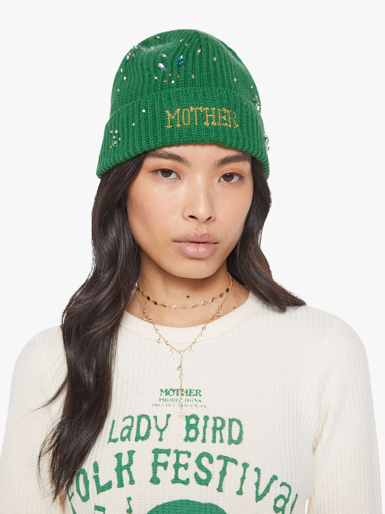 Front view on a model green beanie with MOTHER's name embroidered on the front and beaded details throughout.
