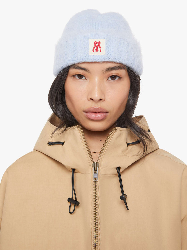 On model view of a blue with an M patch on the front ribbed beanie with a folded hem and cozy fit.