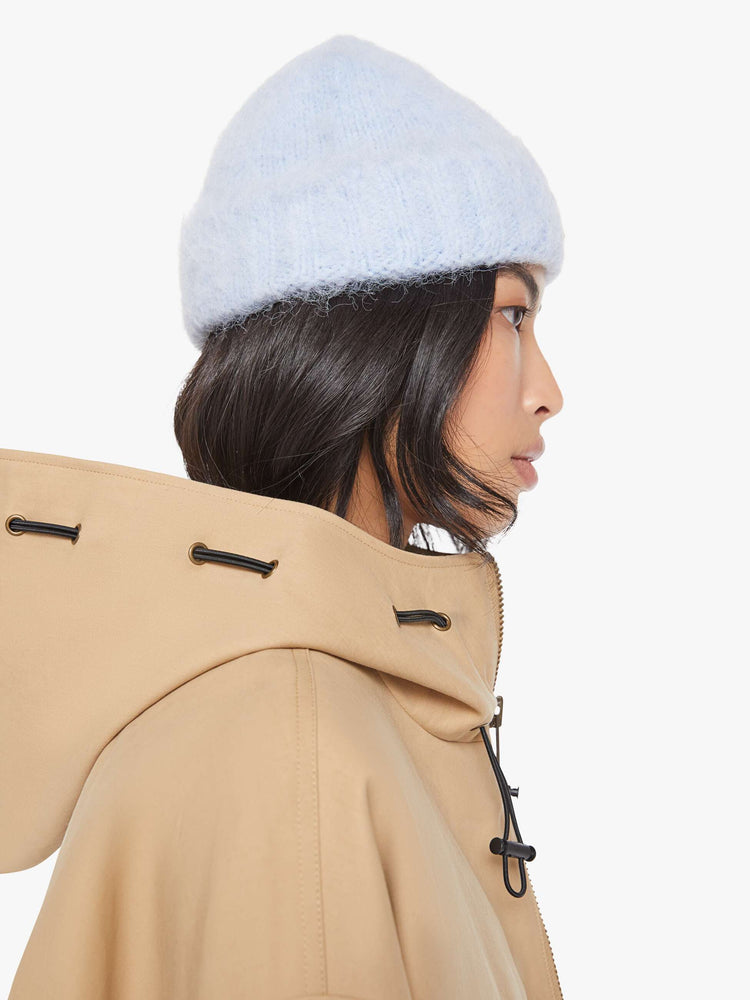 On model side view of a blue with an M patch on the front ribbed beanie with a folded hem and cozy fit.