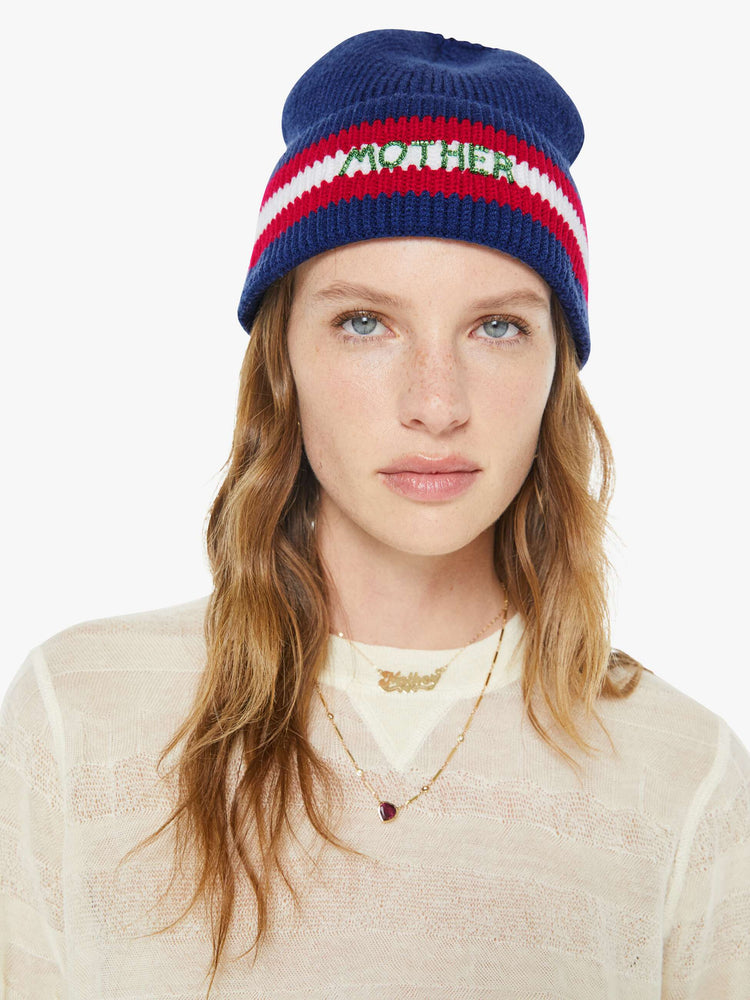 On model view of a woman in a navy with red and white stripes, the beanie features MOTHER's name in green beads on the front.