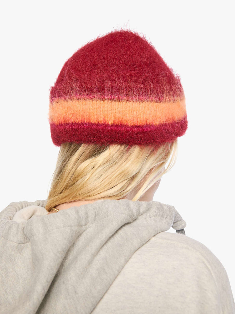 Back view of a woman in red with hot pink and orange stripes knit beanie with a folded brim and MOTHER's name in pearl beads across the front. 