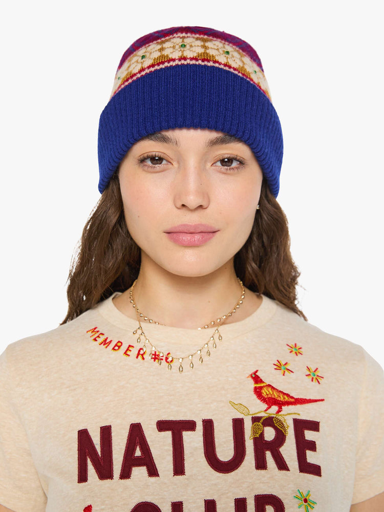Front view of a woman in a knit beanie with a folded brim and small green rhinestone details.