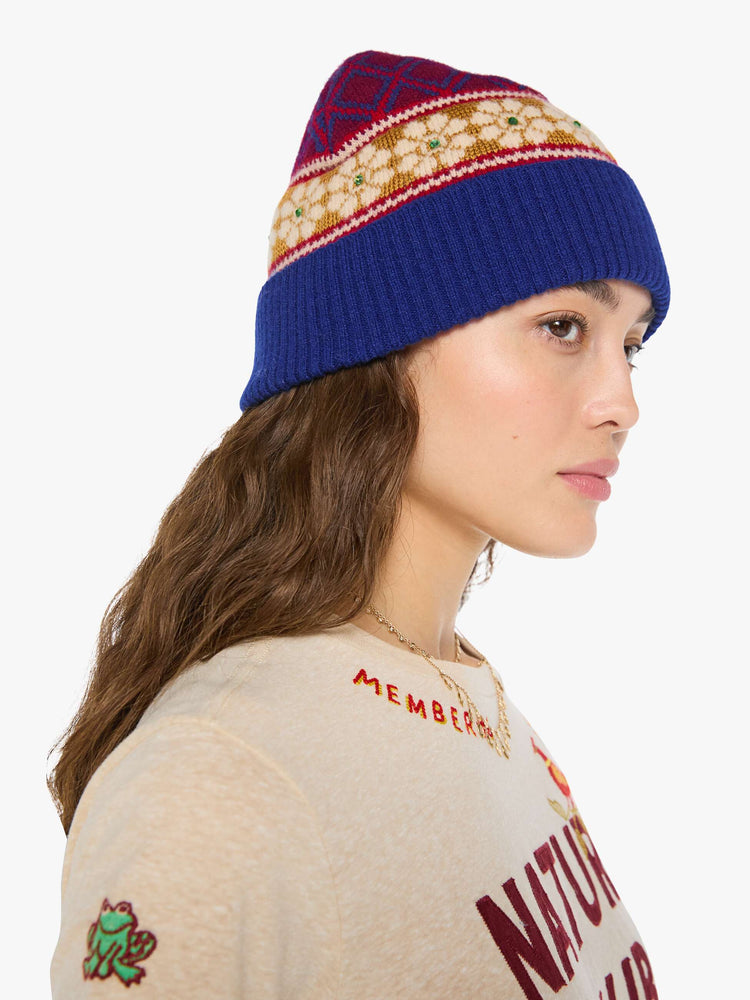 Side view of a woman in a knit beanie with a folded brim and small green rhinestone details.