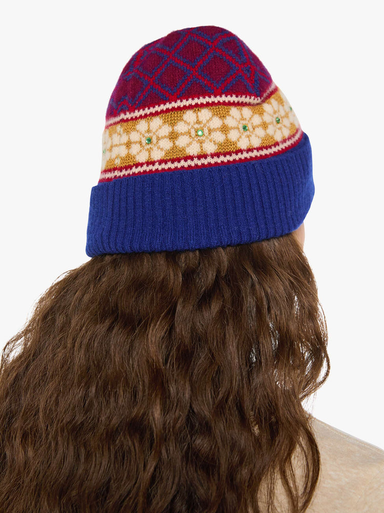 Back view of a woman in a knit beanie with a folded brim and small green rhinestone details.
