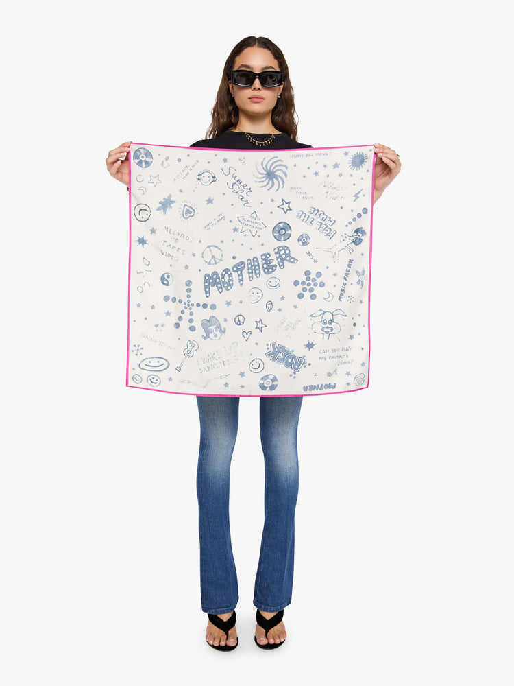 On Mode holding a scarf off-white with hot pink trim and faded blue doodles throughout.