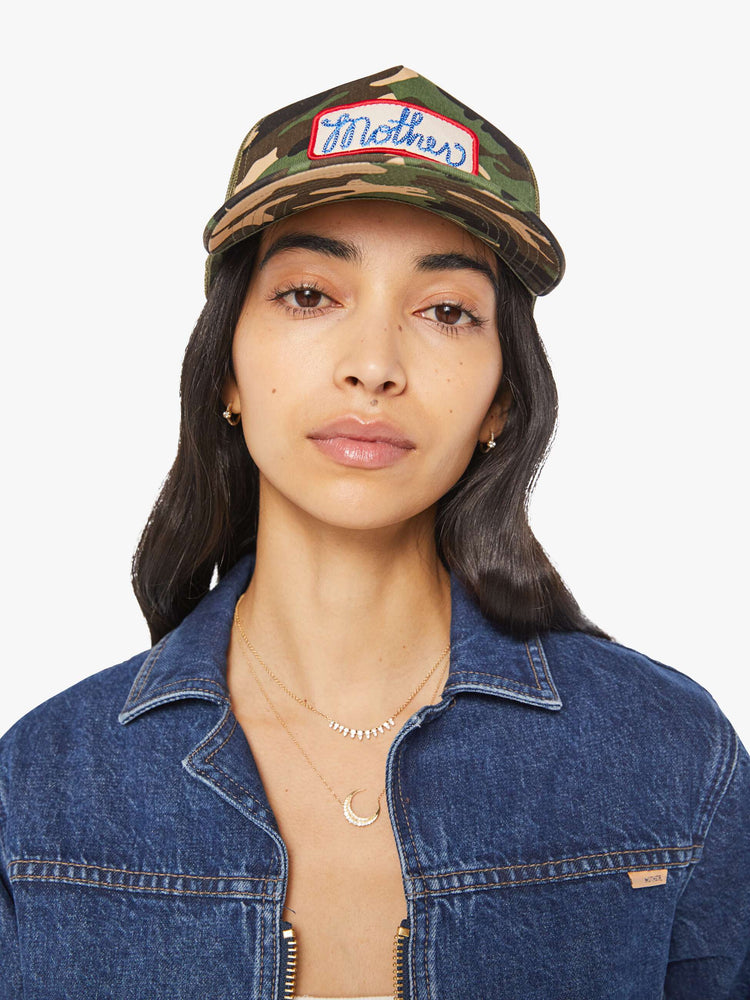 Front view of a woman in a vintage-inspired hat designed in camo featuring a patch with MOTHER's name on the front.