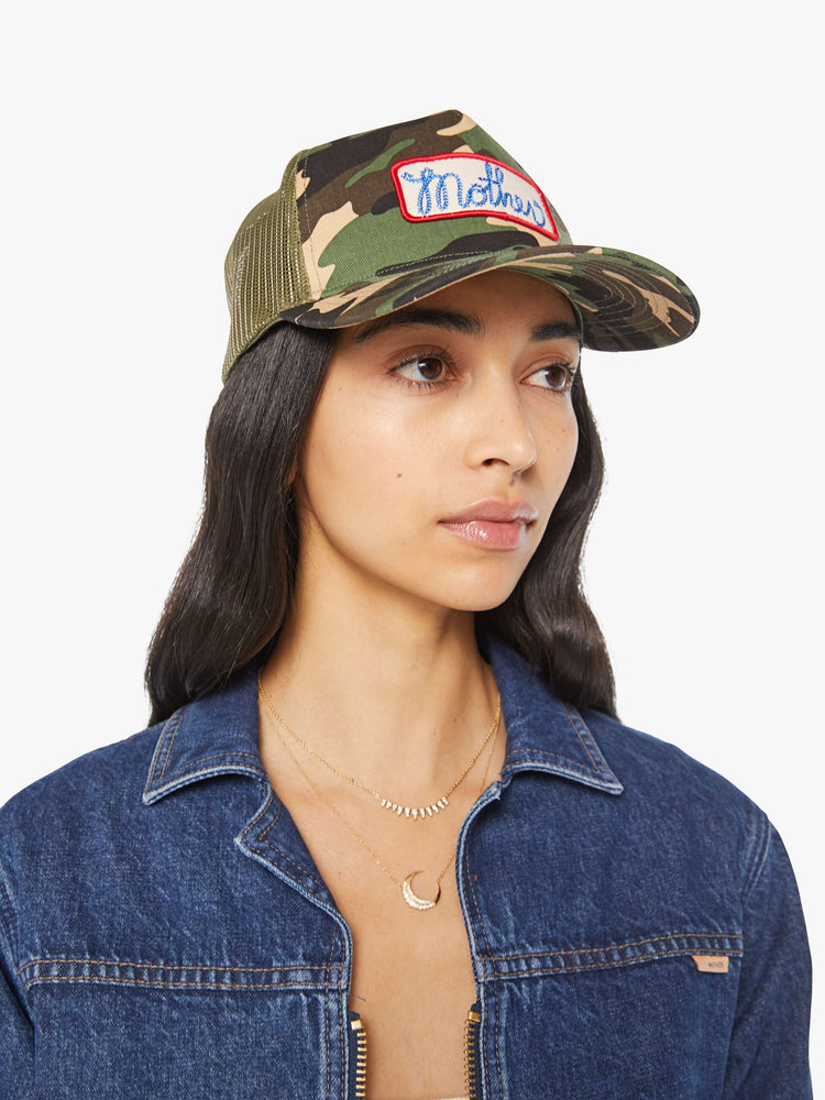 Side view of a woman in a vintage-inspired hat designed in camo featuring a patch with MOTHER's name on the front.