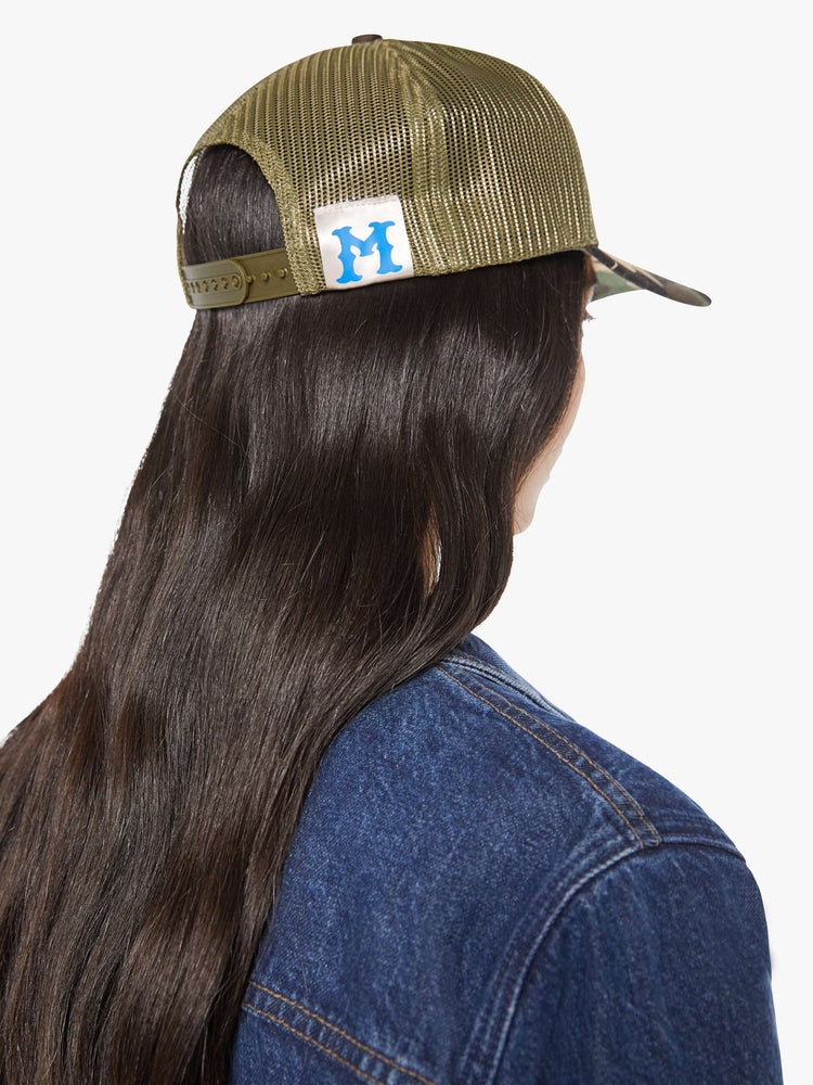 Back view of a woman in a vintage-inspired hat designed in camo featuring a patch with MOTHER's name on the front.