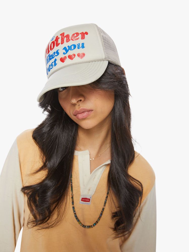 Front view of a vintage-inspired trucker hat designed in a light grey hue with a red and blue text graphic on the front.