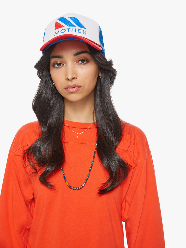 Front view of a woman in a vintage-inspired trucker hat designed in red, white and blue with a raceway-inspired graphic on the front.