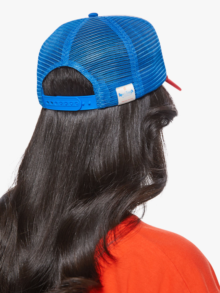 Back view of a woman in a vintage-inspired trucker hat designed in red, white and blue with a raceway-inspired graphic on the front.