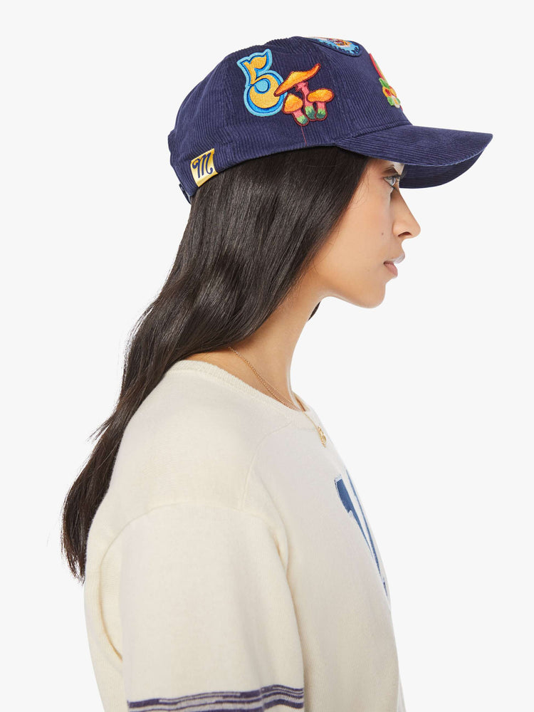 Side view of a woman in a navy corduroy hat with MOTHER's name on the front and colorful patches throughout.