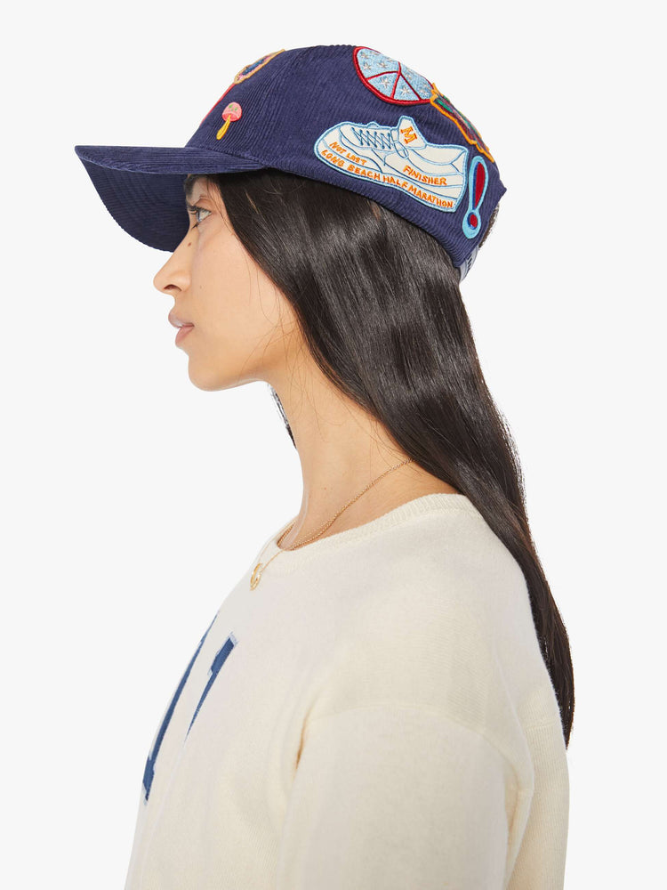 Left side view of a woman in a navy corduroy hat with MOTHER's name on the front and colorful patches throughout.
