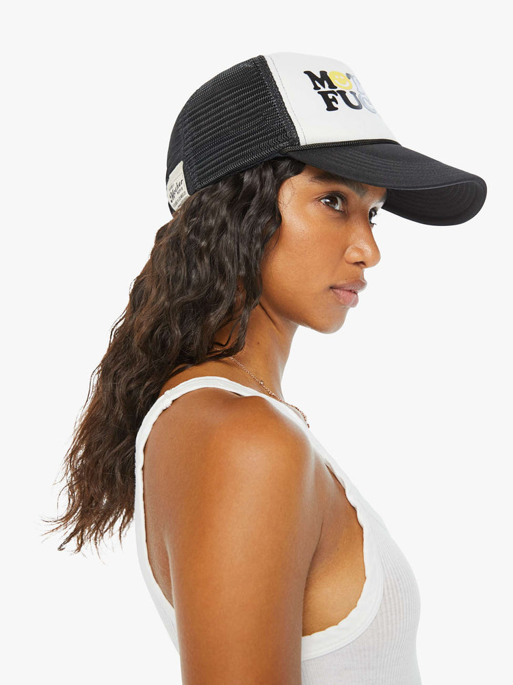 Side view on model of a trucker hat designed in black and white with an explicit text graphic on the front.