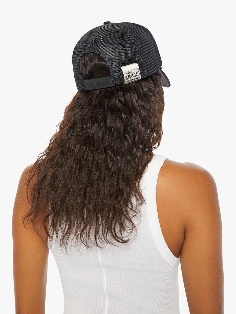 Back view on model of a trucker hat designed in black and white with an explicit text graphic on the front.