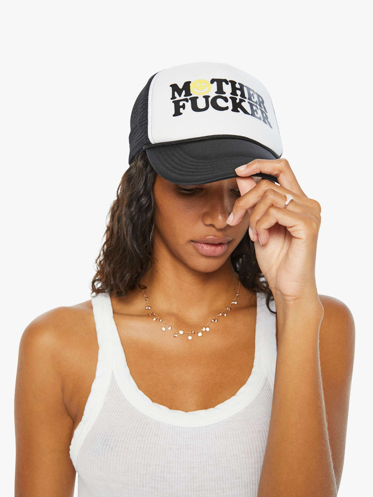 Side angle view on model of a trucker hat designed in black and white with an explicit text graphic on the front.