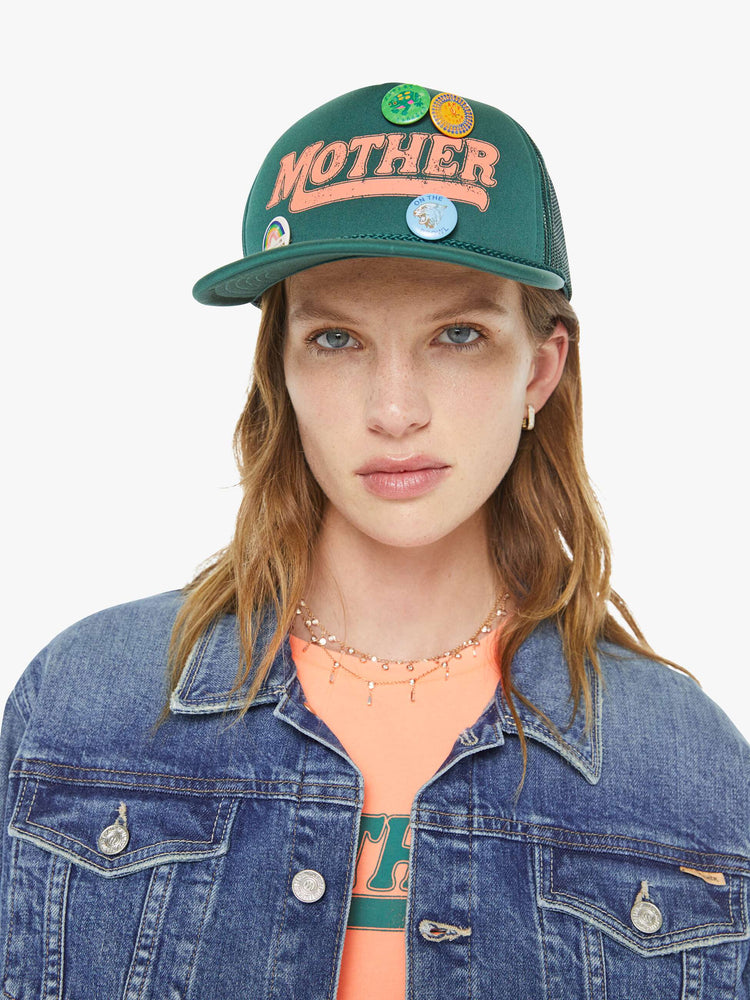 On model view of vintage-inspired hat designed in green featuring retro-inspired pins and MOTHER's name in peach on the front.