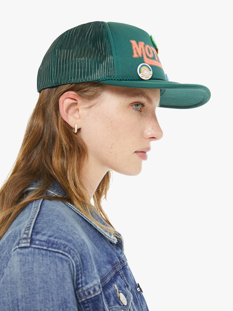 On model side view of vintage-inspired hat designed in green featuring retro-inspired pins and MOTHER's name in peach on the front.