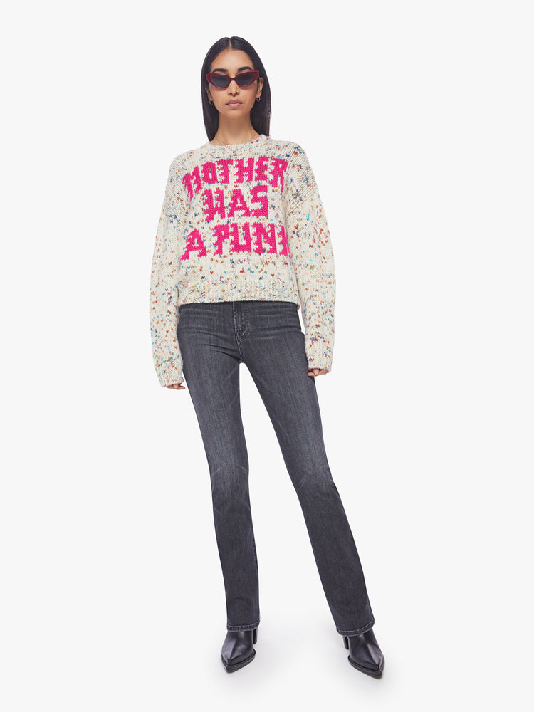 Full body view of a woman crewneck sweater with drop shoulders, long roomy sleeves and a slightly cropped hem in cream with colorful speckles and text in hot pink.