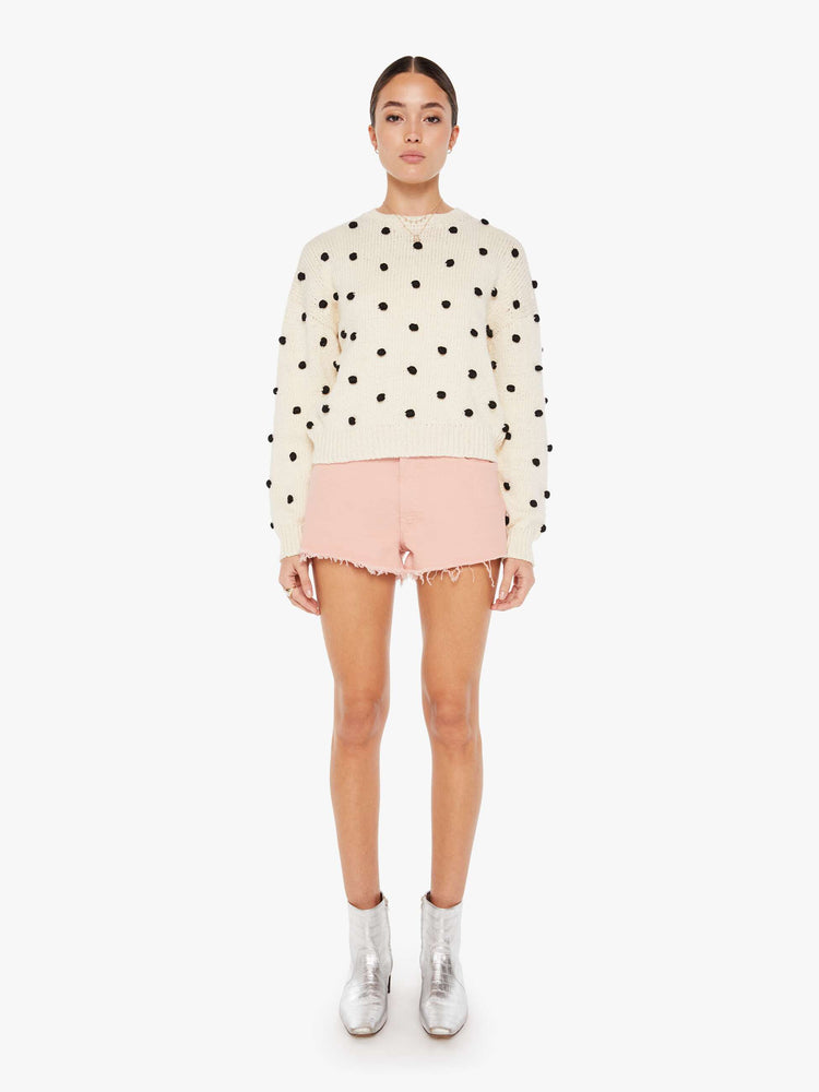 Front full body view of a womens white knit sweater featuring small black pom poms.