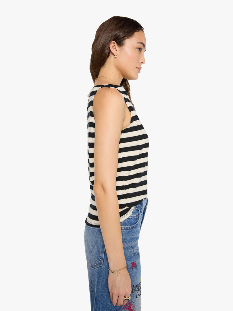 Side view of a woman in a black and off-white stripes sleeveless top with a boat neck and a boxy fit. 