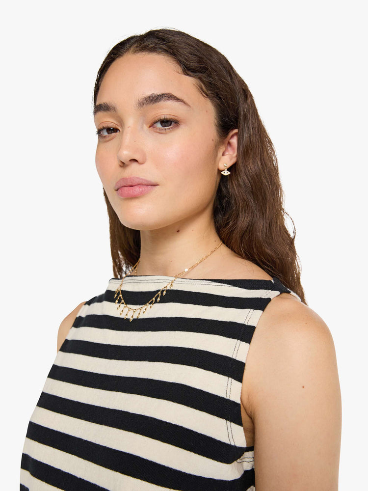 Close up view of a woman in a black and off-white stripes sleeveless top with a boat neck and a boxy fit. 