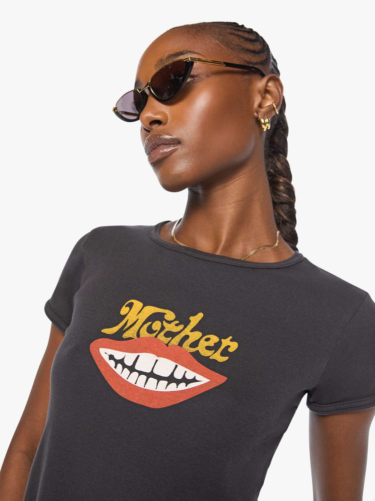 Close up view of a woman in a faded black a smiling mouth graphic and MOTHER's name in golden yellow on the front.
