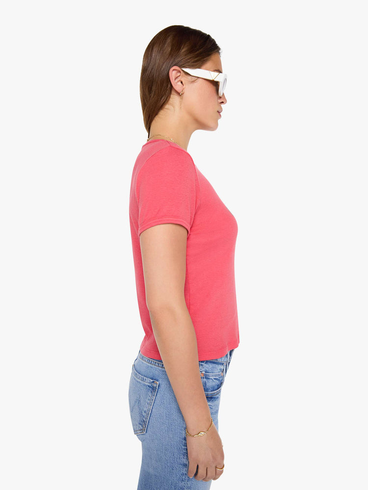 Sid view of a woman in a coral crewneck tee with extra-short sleeves and a cropped hem.